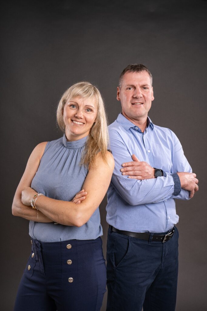 Doreen Maaß und Michael, das Team hinter Erfolgsverliebt, vor grauem Studiohintergrund