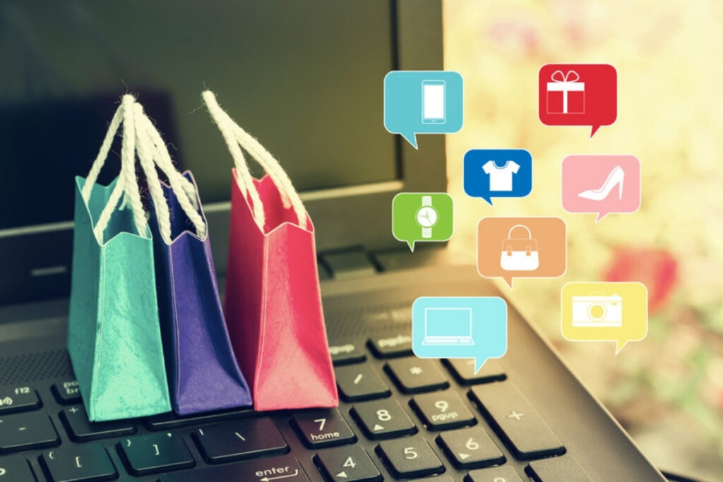 Bunte Papiertüten auf einer Laptop-Tastatur, daneben Symbole für verschiedene Produktkategorien