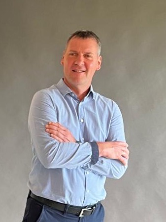Michael mit verschränkten Armen vor grauem Studiohintergrund